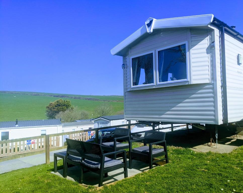 纽基4 Berth Couples and Family Caravan in Beautiful Newquay Bay Resort的坐在甲板上的小房子,带椅子