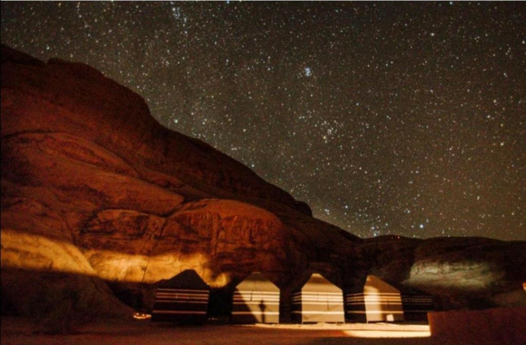 瓦迪拉姆Wadi rum Local guide camp的山下星空 ⁇ ,下方有楼房