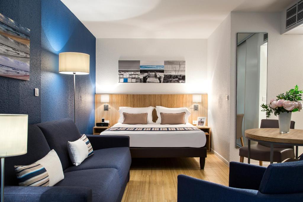 戛纳Citadines Croisette Cannes的酒店客房,配有床和沙发
