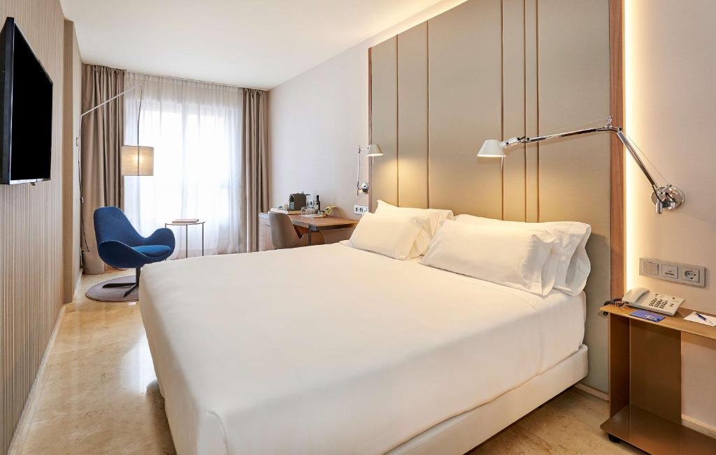 洛格罗尼奥新罕布什尔州里奥哈酒店的酒店客房设有一张白色大床和一张蓝色椅子。