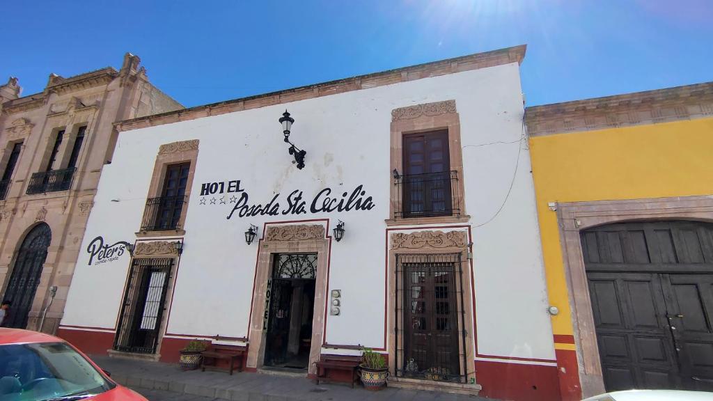 赫雷斯加西亚萨利纳斯OYO Posada Santa Cecilia, Jerez Zacatecas的白色的建筑,旁边标有标志