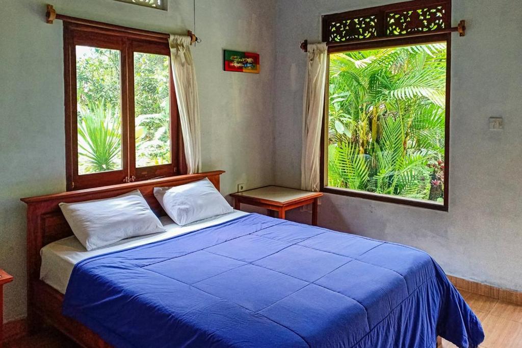 贾蒂卢维Dina Home Stay at Desa Wisata Wongayagede的一间卧室设有蓝色的床和大窗户