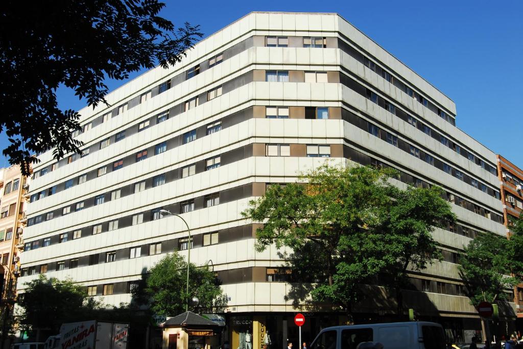 马德里戈雅75号公寓的一座高大的白色建筑,前面有一棵树