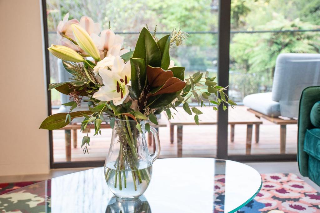 瓦纳卡Brookside Central Wanaka Luxury Apartment的花瓶,花朵放在桌子上