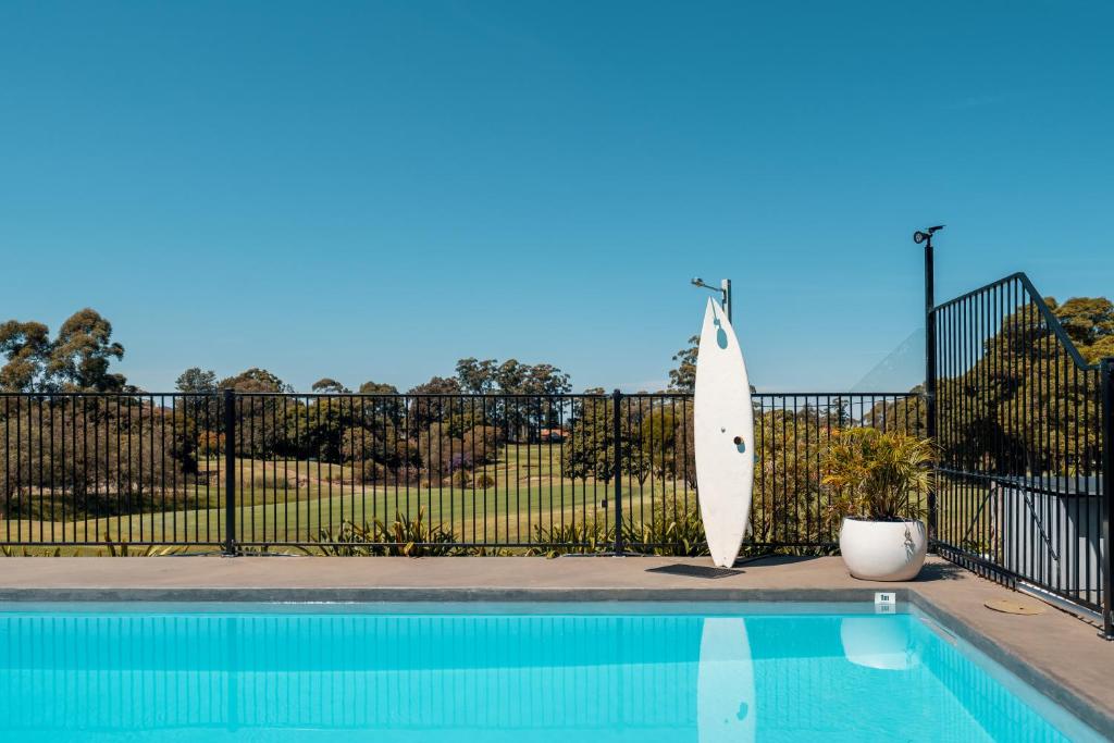 悉尼The Select Inn Ryde的靠在游泳池旁的围栏上的冲浪板
