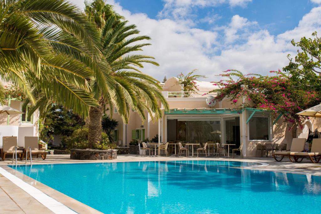 卡马利乔安娜别墅酒店的一座棕榈树游泳池和一座房子