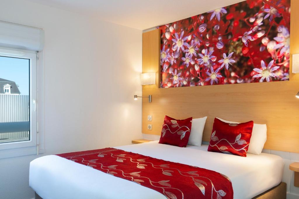 奥尔良Fasthotel Orleans Zénith的卧室配有一张大床,墙上挂有绘画作品