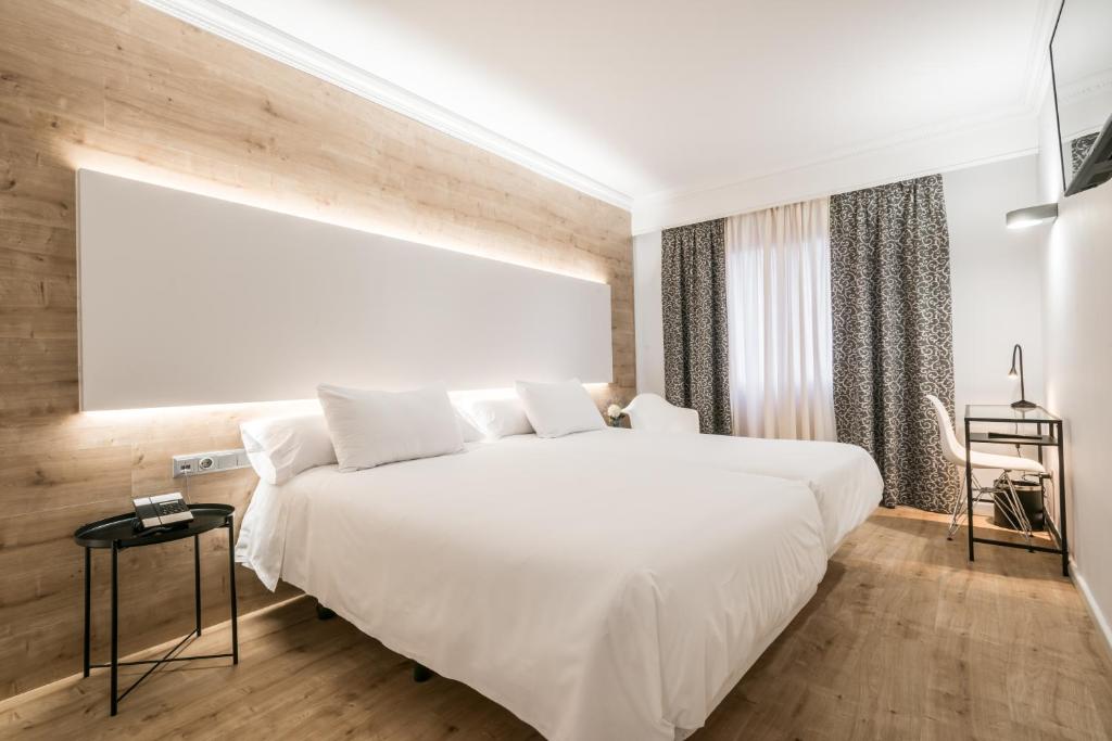 莱里达三思公园酒店的卧室配有一张白色的大床,铺有木地板