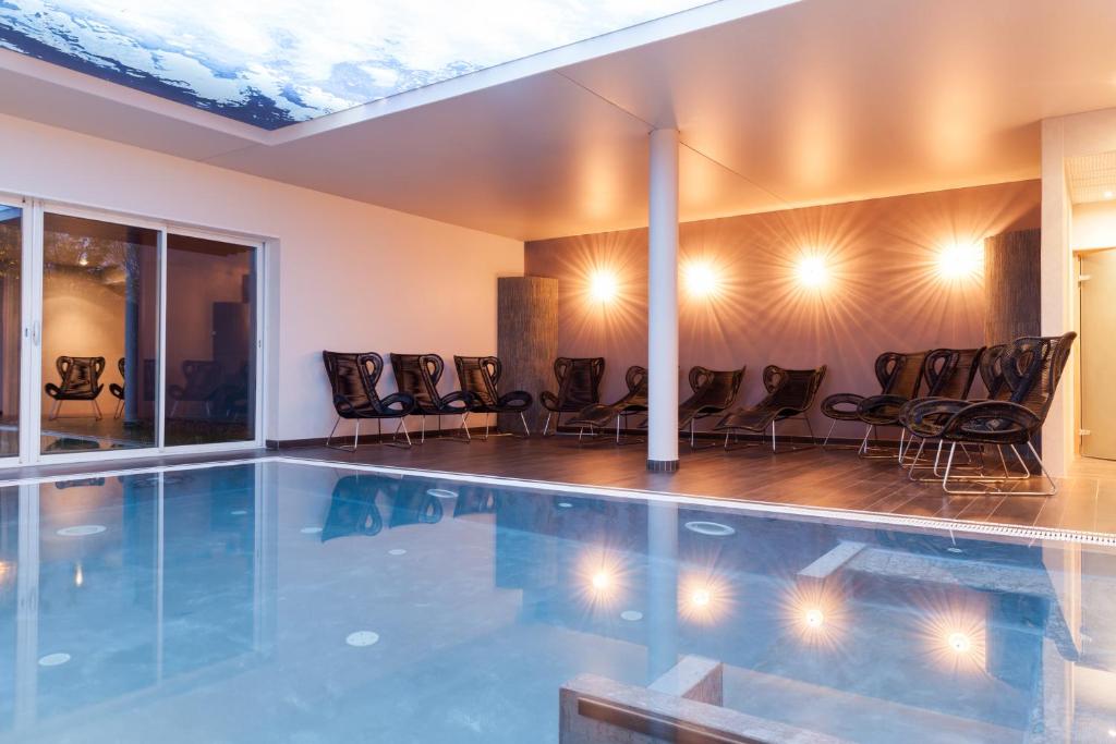 蒙贝利亚尔Charme Hôtel et Spa, Montbéliard Sud的一个带椅子的游泳池的房间