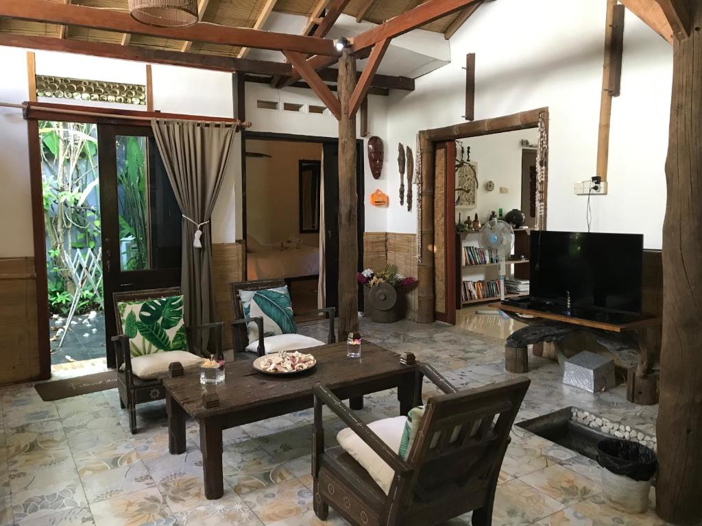 圣吉吉Frangipani Garden Villa的客厅配有桌椅和电视。