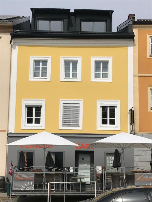 Haslach an der MühlPension Sunnseitn - Gasthof - Café - Weinkeller的前面有桌子和遮阳伞的黄色建筑