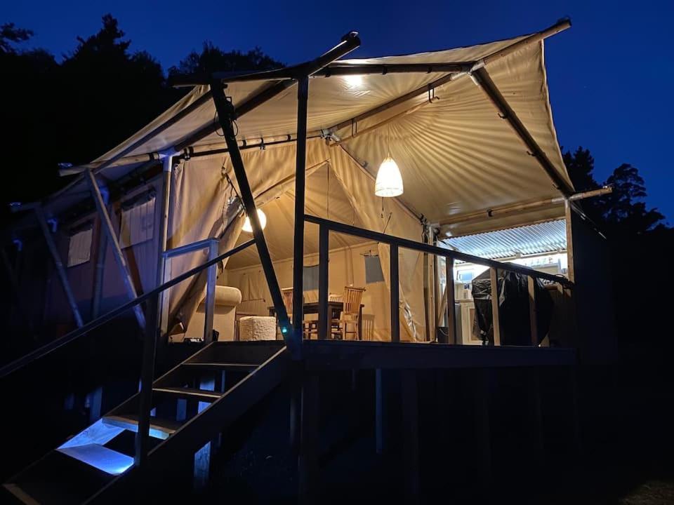 WaipapaLynx Lodge的帐篷在晚上配有桌椅
