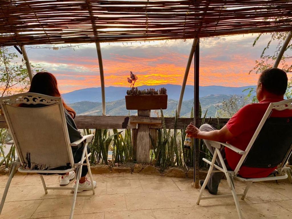 塔斯科·德·阿拉尔孔Hotel SPA Campestre Los Adobes的坐在椅子上看日落的男人和女人