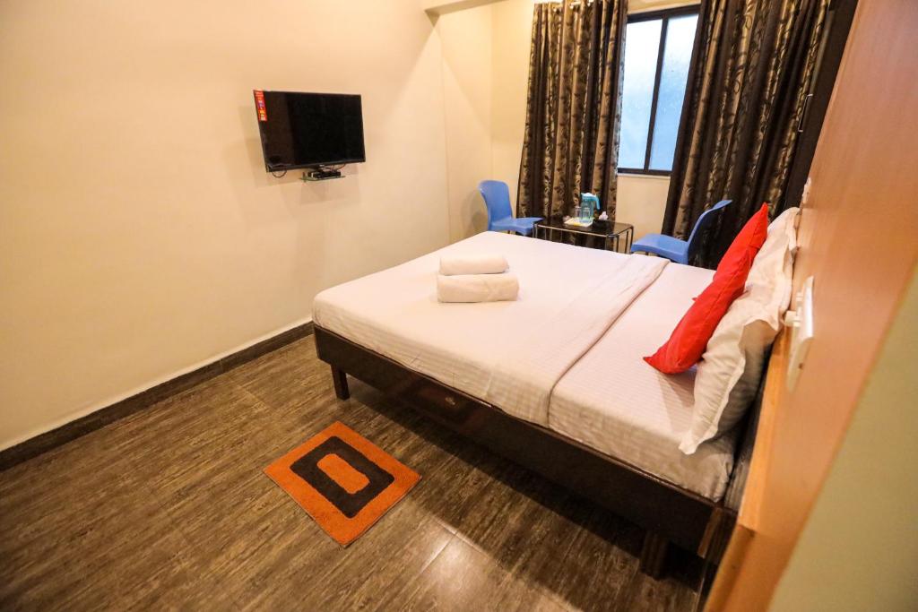 罗纳瓦拉Hotel Sai Niwas的一间卧室配有一张床、两把椅子和电视