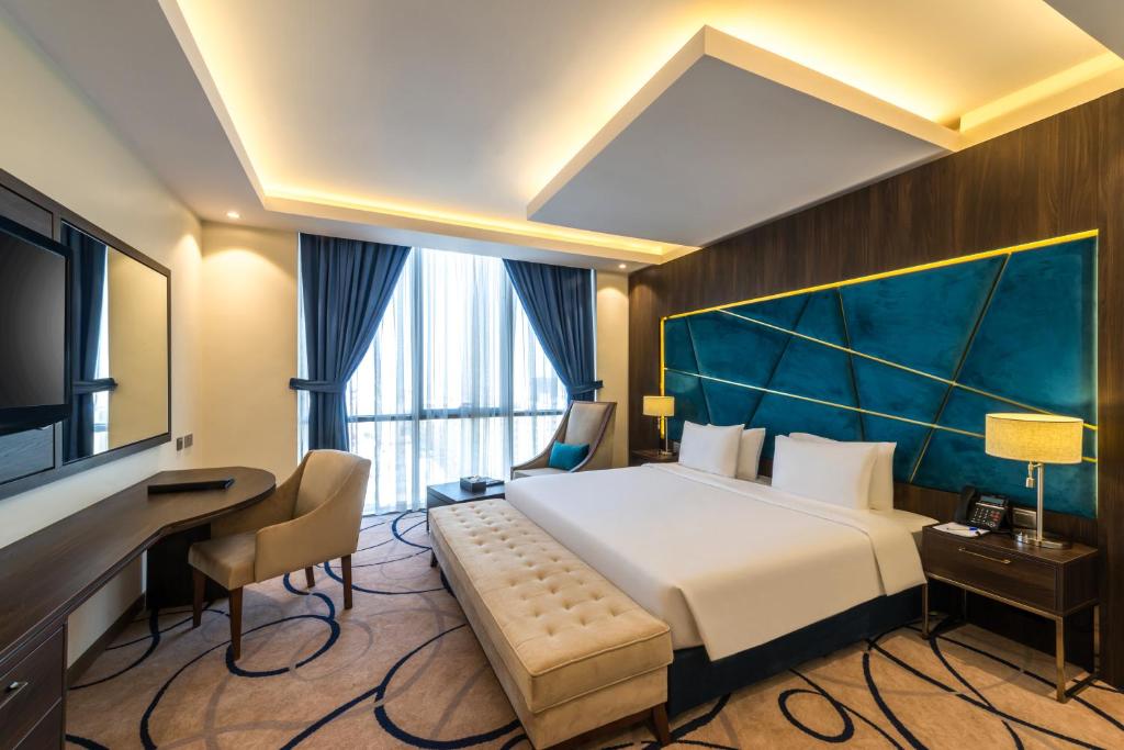 利雅德Warwick Riyadh Al Wezarat的酒店客房设有一张大床和一张书桌。