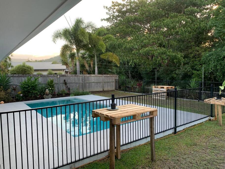 道格拉斯港Beautiful large home available in tropical north Queensland的游泳池旁的木桌