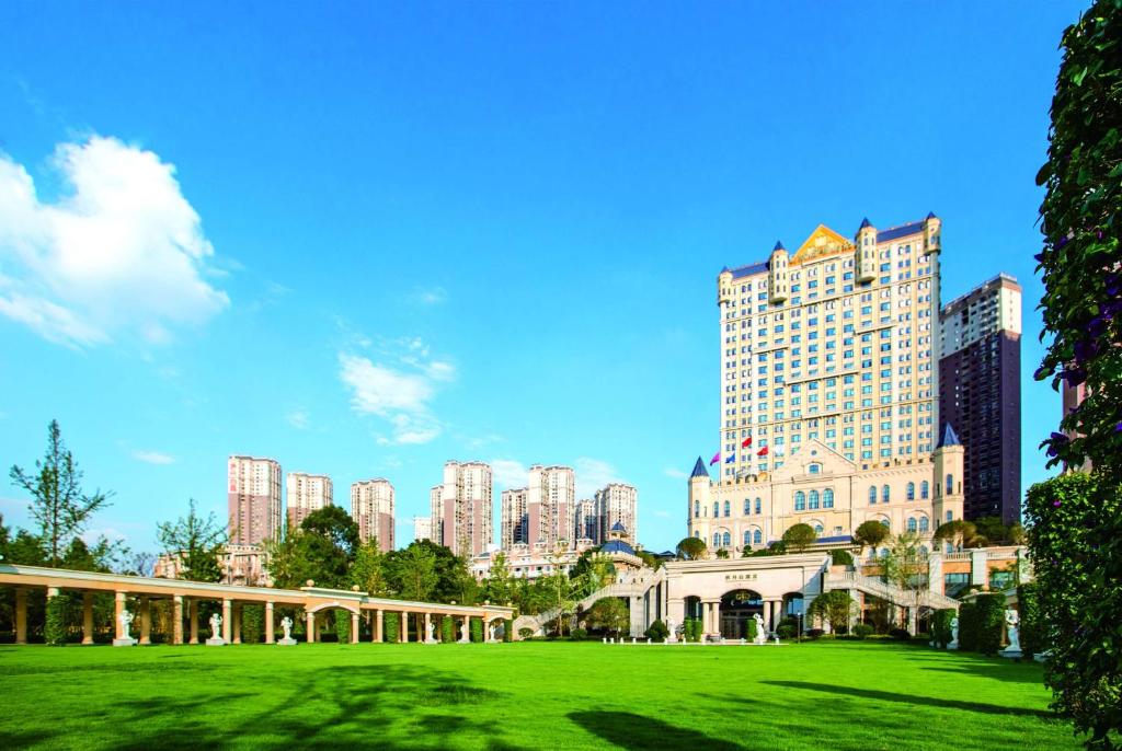 昆明昆明亿壕城堡温德姆至尊酒店的一座绿色公园,位于一座高楼城市前面