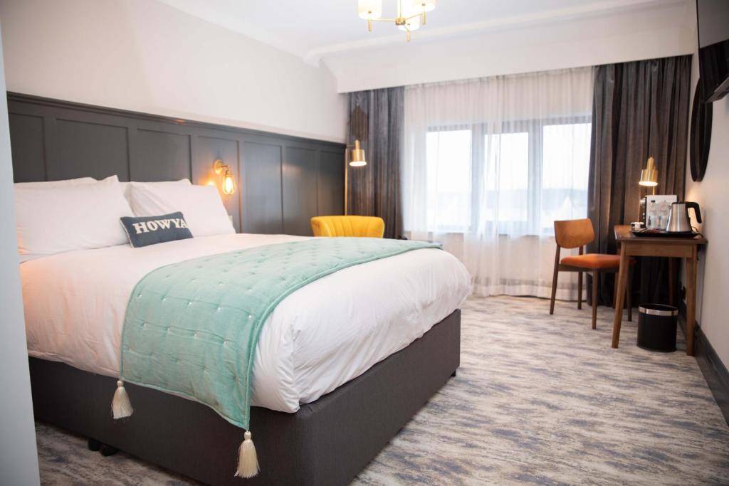 GeesalaErris Coast Hotel的酒店客房设有一张大床和一张书桌。