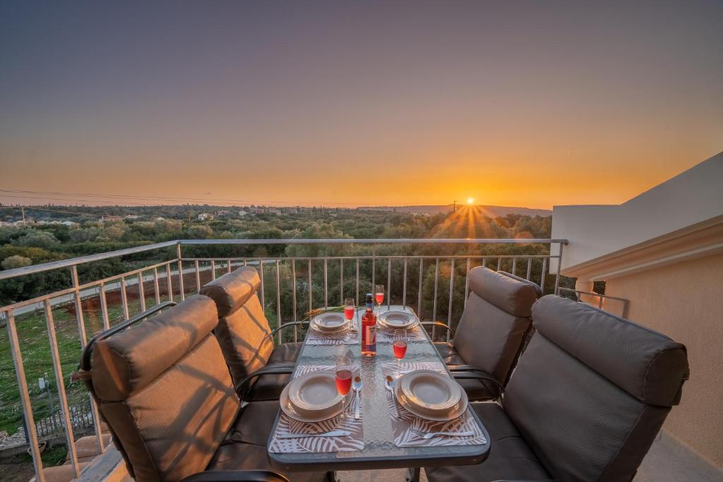 凯法利尼亚岛Mimoza's Apartment的阳台的桌椅享有日落美景