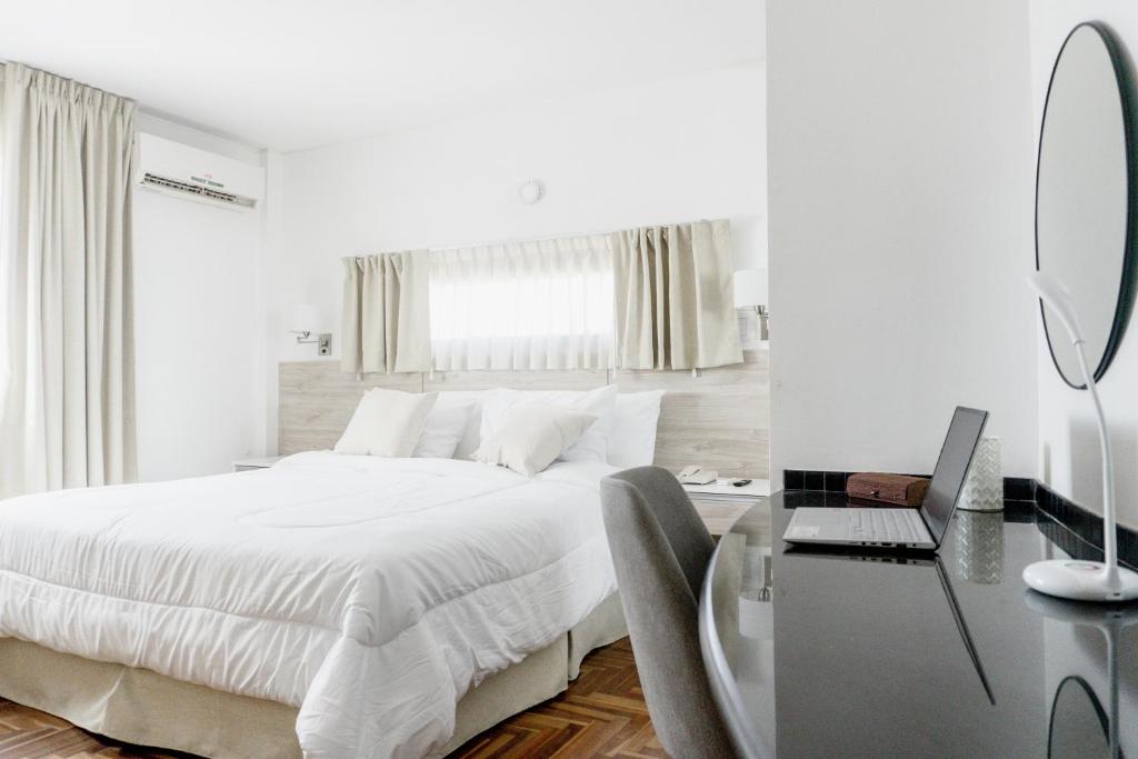 罗萨里奥Mediterráneo Hotel y Spa的白色卧室配有一张床和一张带镜子的书桌