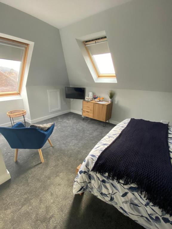 CaolAttic views的一间卧室配有一张床和一把椅子,还有两个窗户