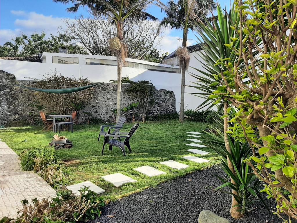 拉戈阿Vila Nikau - Garden by the Sea的花园设有2张长椅、1张桌子和吊床