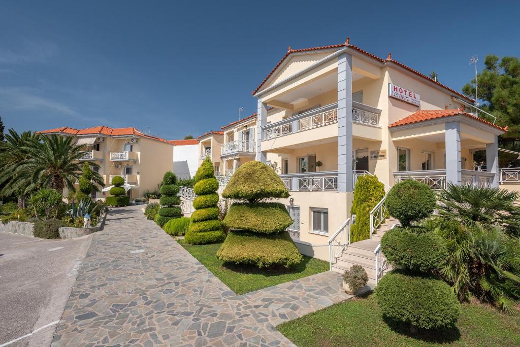 米里纳Hotel Sotiris Superior Apartments的一座大建筑前面有灌木和树木