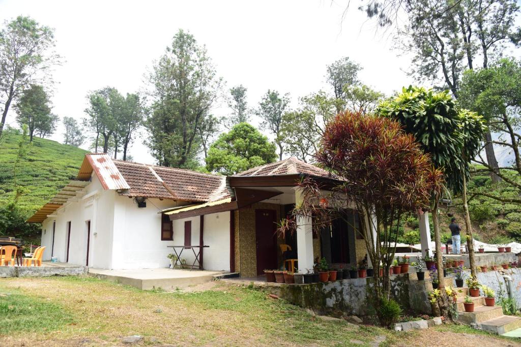 蒙纳Munnar Home Stay的一座白色的小房子,后面有一座绿色的山丘