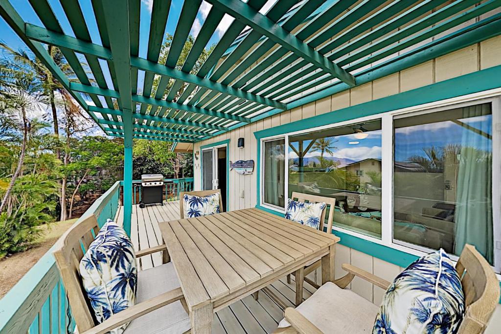 维雷亚Nahenahe Cottage的露台设有木桌和椅子,甲板上设有