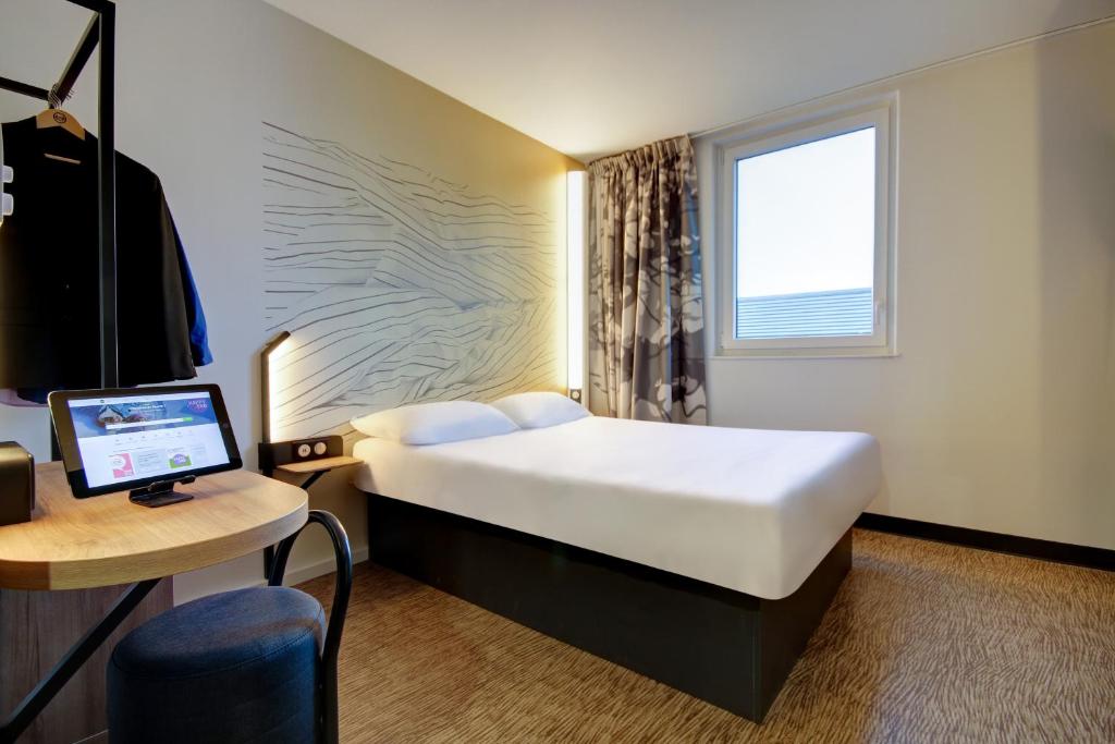 埃佩尔奈B&B HOTEL Epernay的酒店客房配有一张床和一张带电脑的书桌