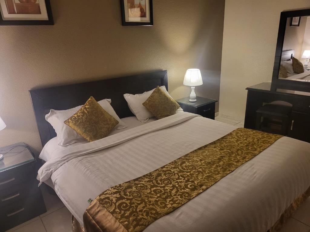 艾卜哈Safwt Aldyar Furnished Units的卧室配有带金色枕头的大型白色床