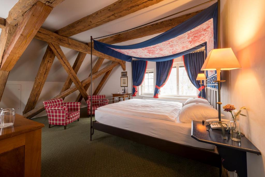高莱茵河畔布辛根艾特莱茵河畔磨坊酒店&餐厅的一间卧室配有一张天蓬床和两把椅子