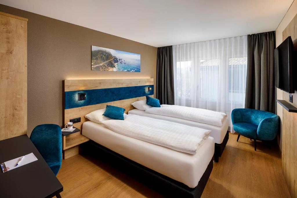 苏黎世加利福尼亚酒店的两张位于酒店客房的床,配有蓝色椅子