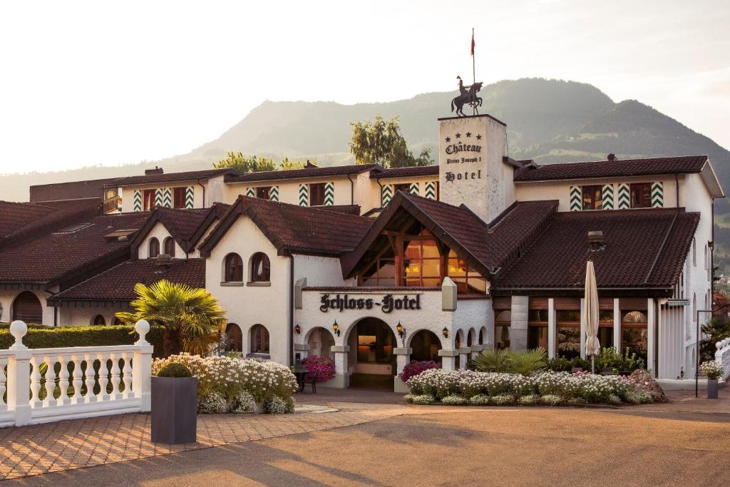 屈斯纳赫特Swiss-Chalet Merlischachen - Romantik Schloss-Hotel am See的一座白色的大建筑,背景是一座山