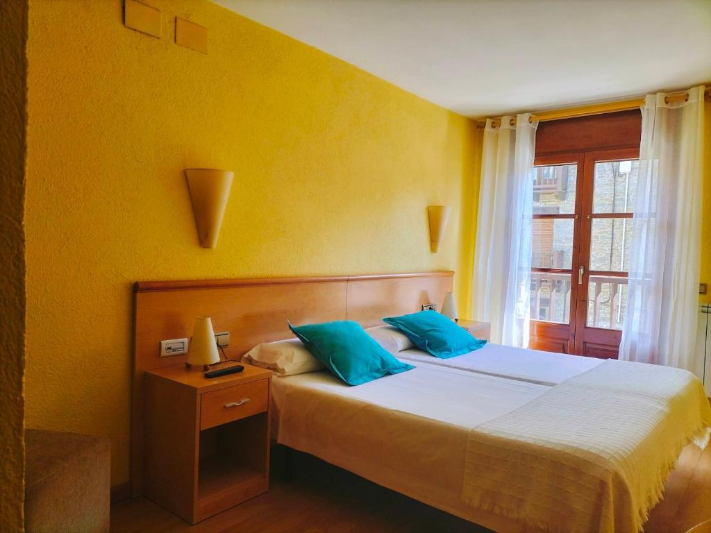 CantonigrosHostal Cabrerès的一间卧室配有一张带蓝色枕头的床和一扇窗户。