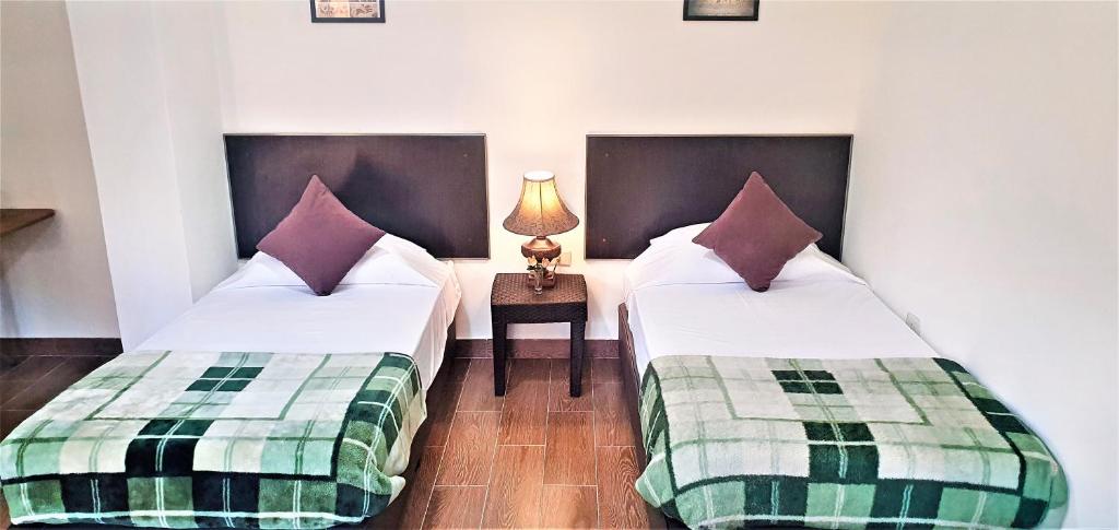 马达巴GMT Residence的客房设有两张床和一张带台灯的桌子。