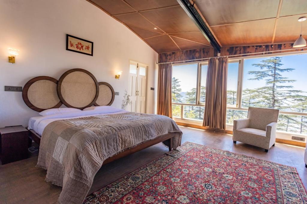 西姆拉Seclude Shimla, Taraview的一间卧室设有一张大床、一把椅子和窗户。
