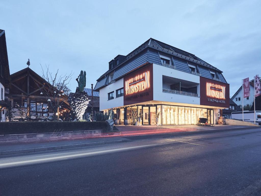 农嫩霍恩Hotel Hornstein - Weingut, Vinothek & Gastronomie的街道边有 ⁇ 虹灯标志的建筑物