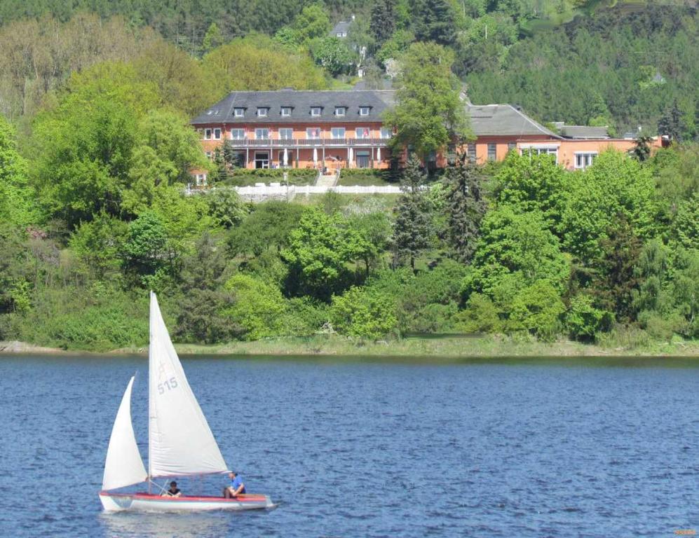 萨尔堡希布里克酒店 的湖面上的帆船,有房子的背景
