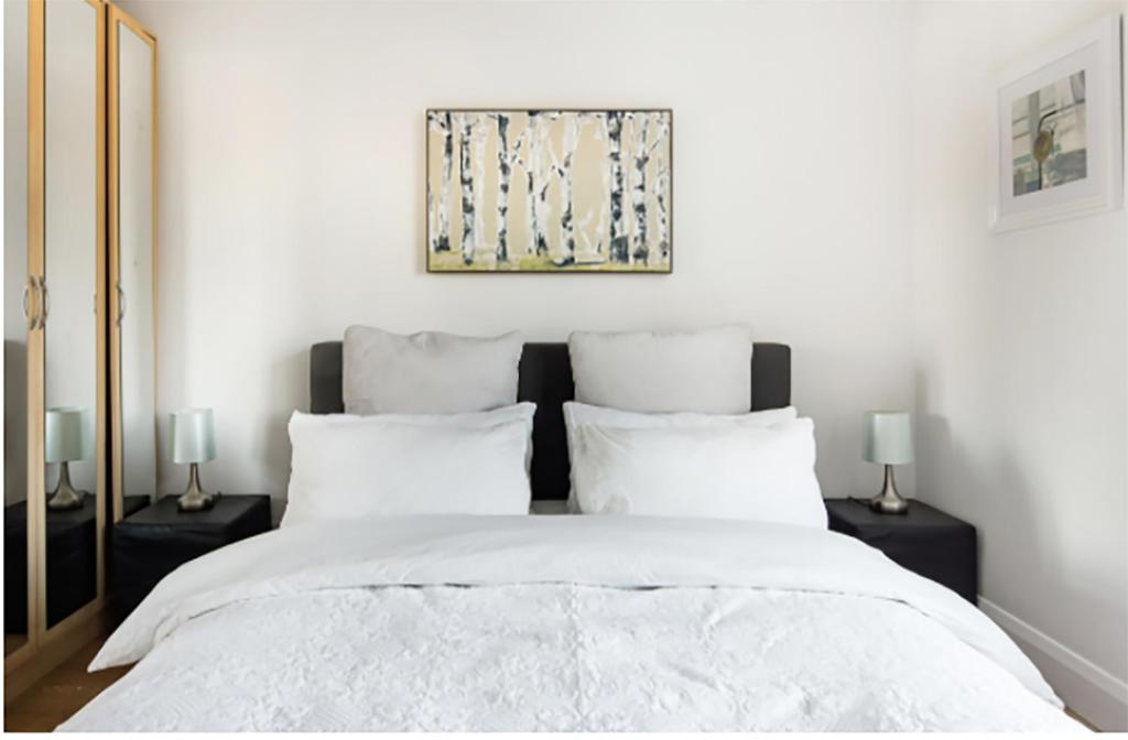 伦敦绝美伊斯特芬奇利公寓的一间卧室配有一张带两盏灯的大型白色床。