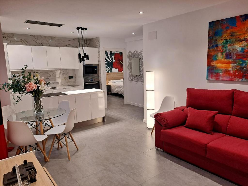 贝尼多姆LEVANTE SUITES的一间带红色沙发的客厅和一间厨房