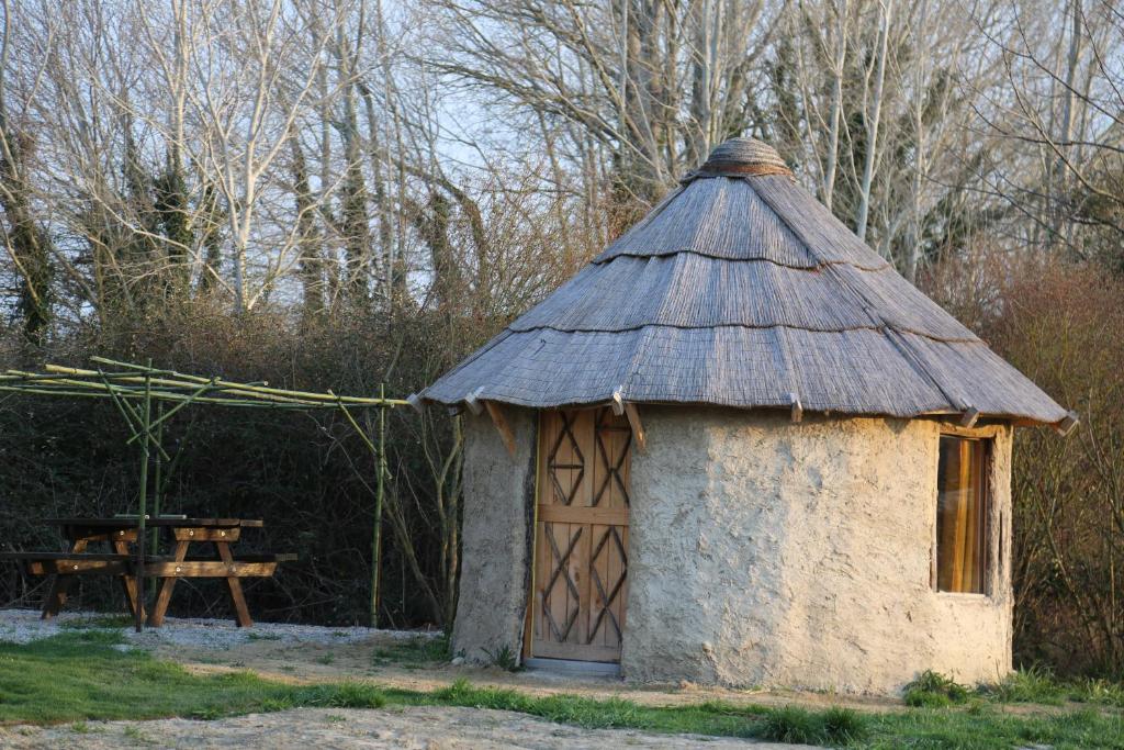 VillelaureLA HUTTE MASSAÏ的一座带屋顶的小建筑,配有野餐桌