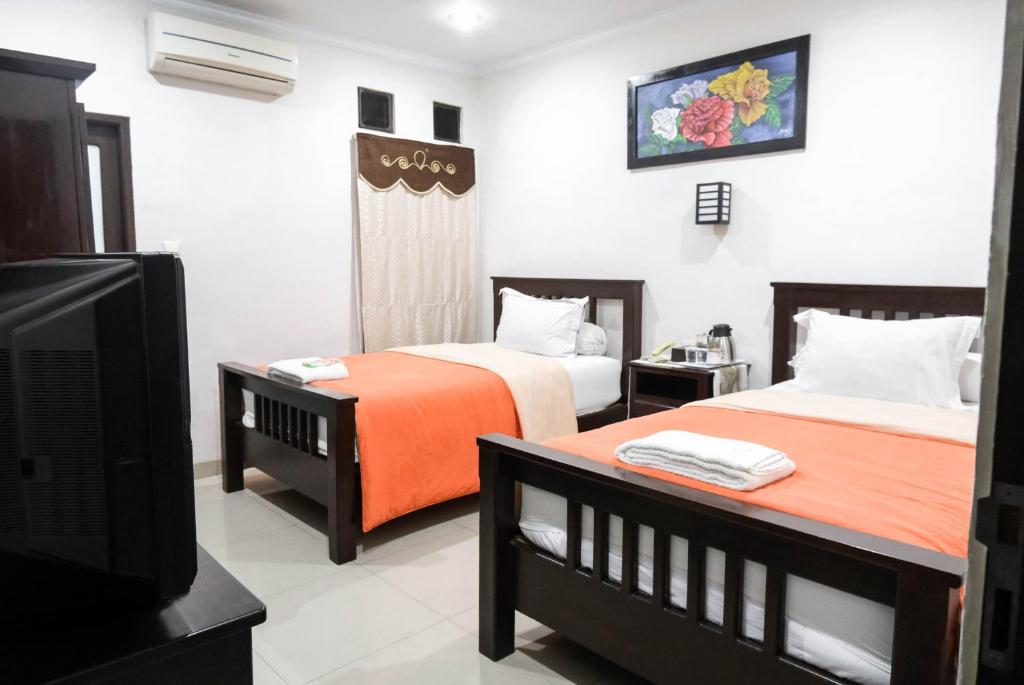 棉兰Pasola Guest House的一间酒店客房,设有两张床和电视