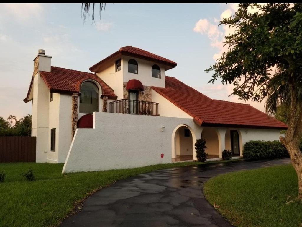 迈阿密Bella Stanza的白色的房子,有红色的屋顶和车道