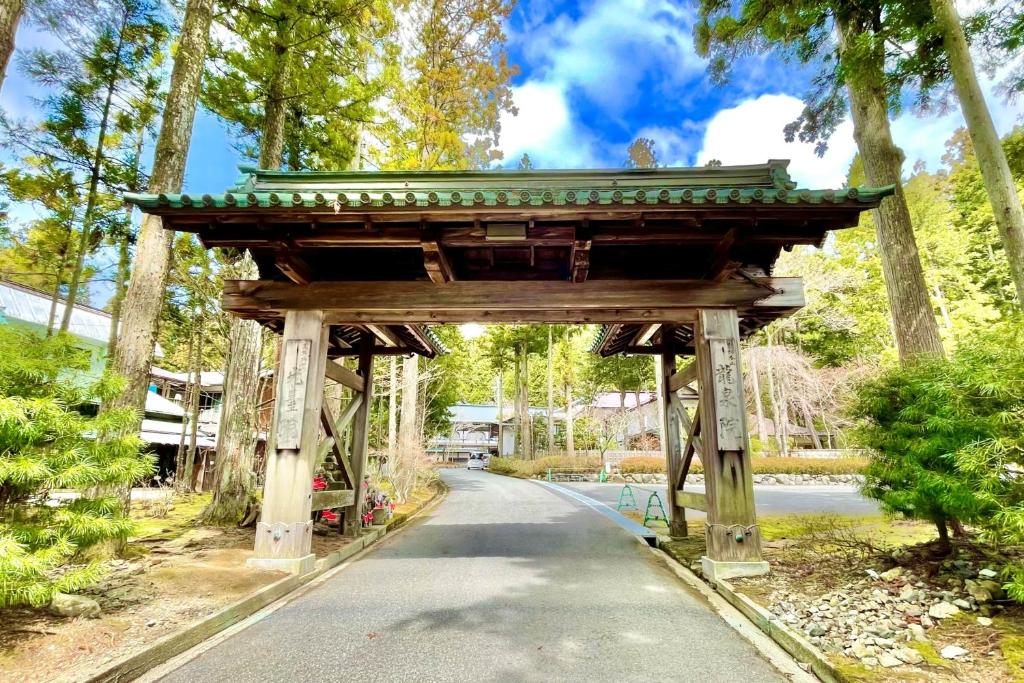 高野山高野山 宿坊 龍泉院 -Koyasan Shukubo Ryusenin-的一条有道路的公园中的木拱门