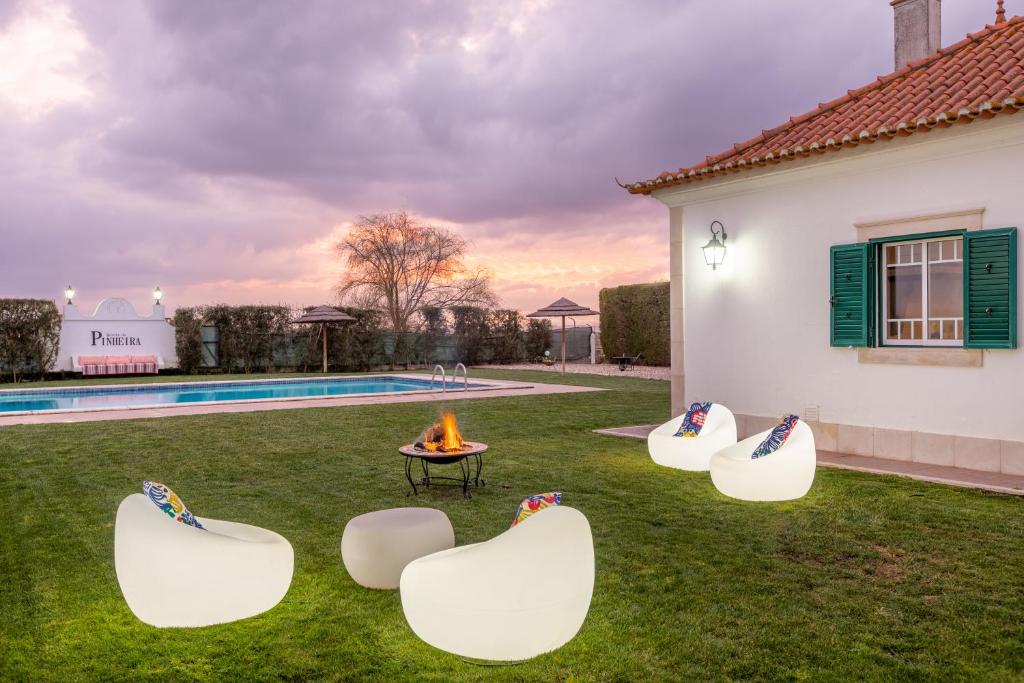 AlpiarçaQuinta da Pinheira Lezíria的后院设有四把白色椅子和一个火坑