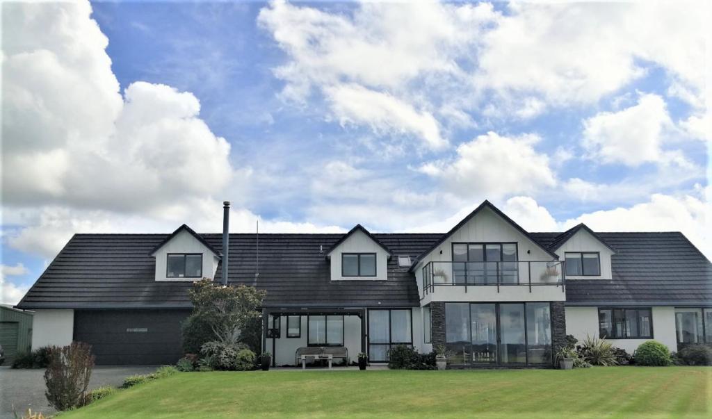 TawharanuiRuru Lodge的一座黑屋顶和绿色庭院的房子
