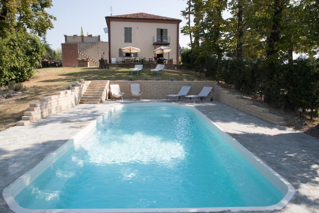 特雷伊索圣斯特凡内托度假别墅酒店的一个带椅子的游泳池和一个背景房子