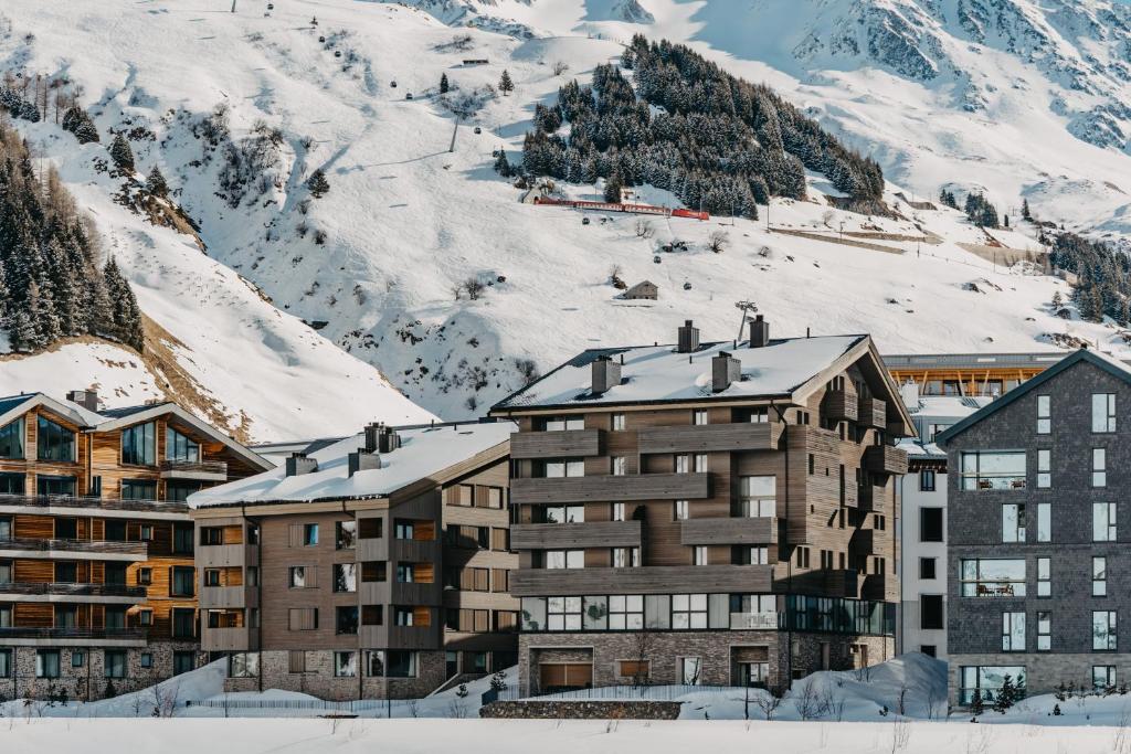 安德马特Andermatt Alpine Apartments的雪覆盖的山前的建筑物