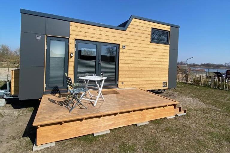 ElsflethWinzig Wohnen Tiny House Frigg direkt am Weserstrand的一个小房子,设有甲板和桌椅